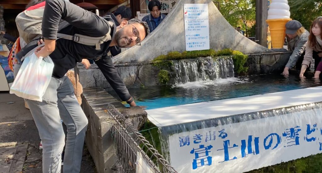 A man dipping his hands in ice cold water from Mount Fuji